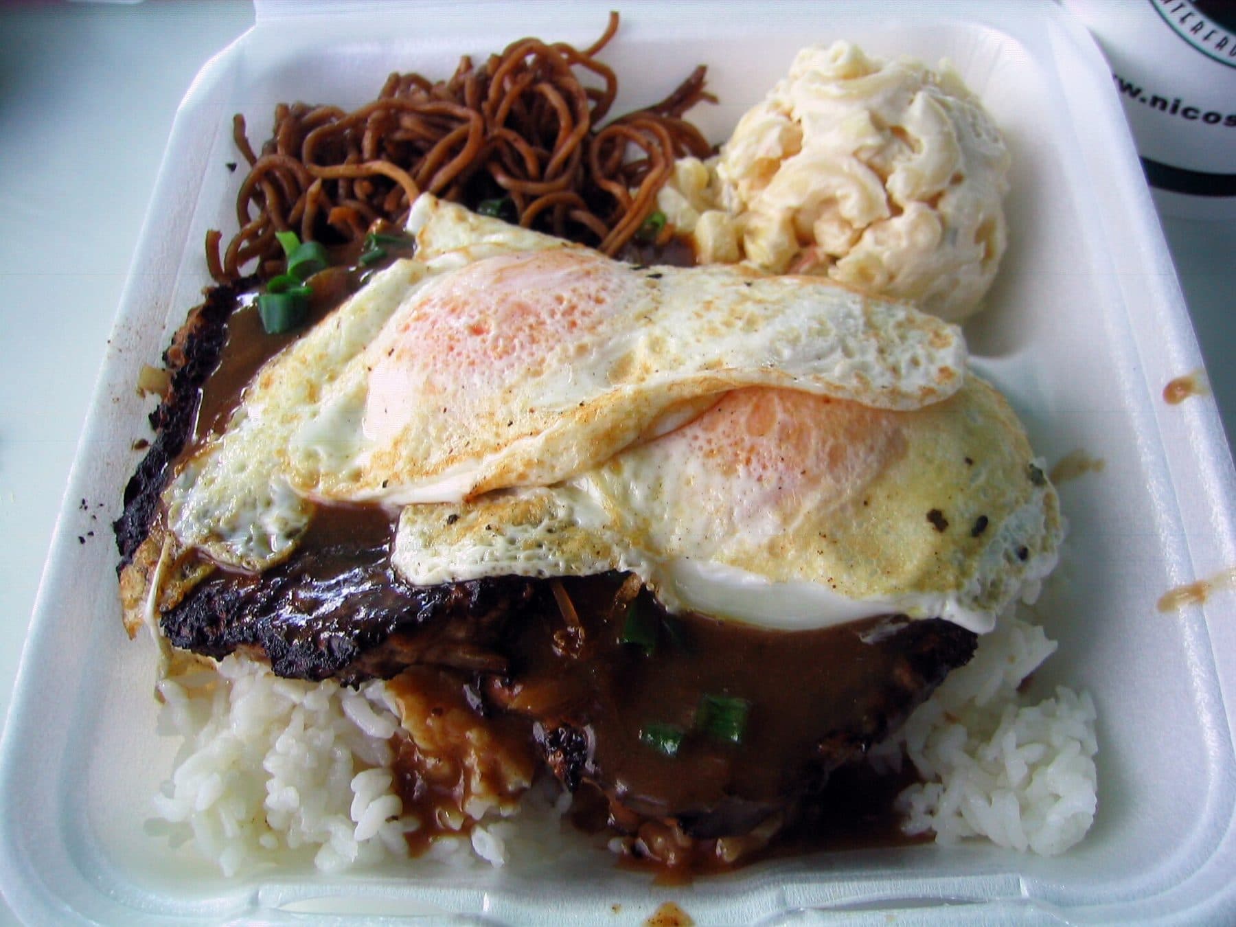 A plate-lunch loco moco: rice and a hamburger patty under fried eggs and brown gravy