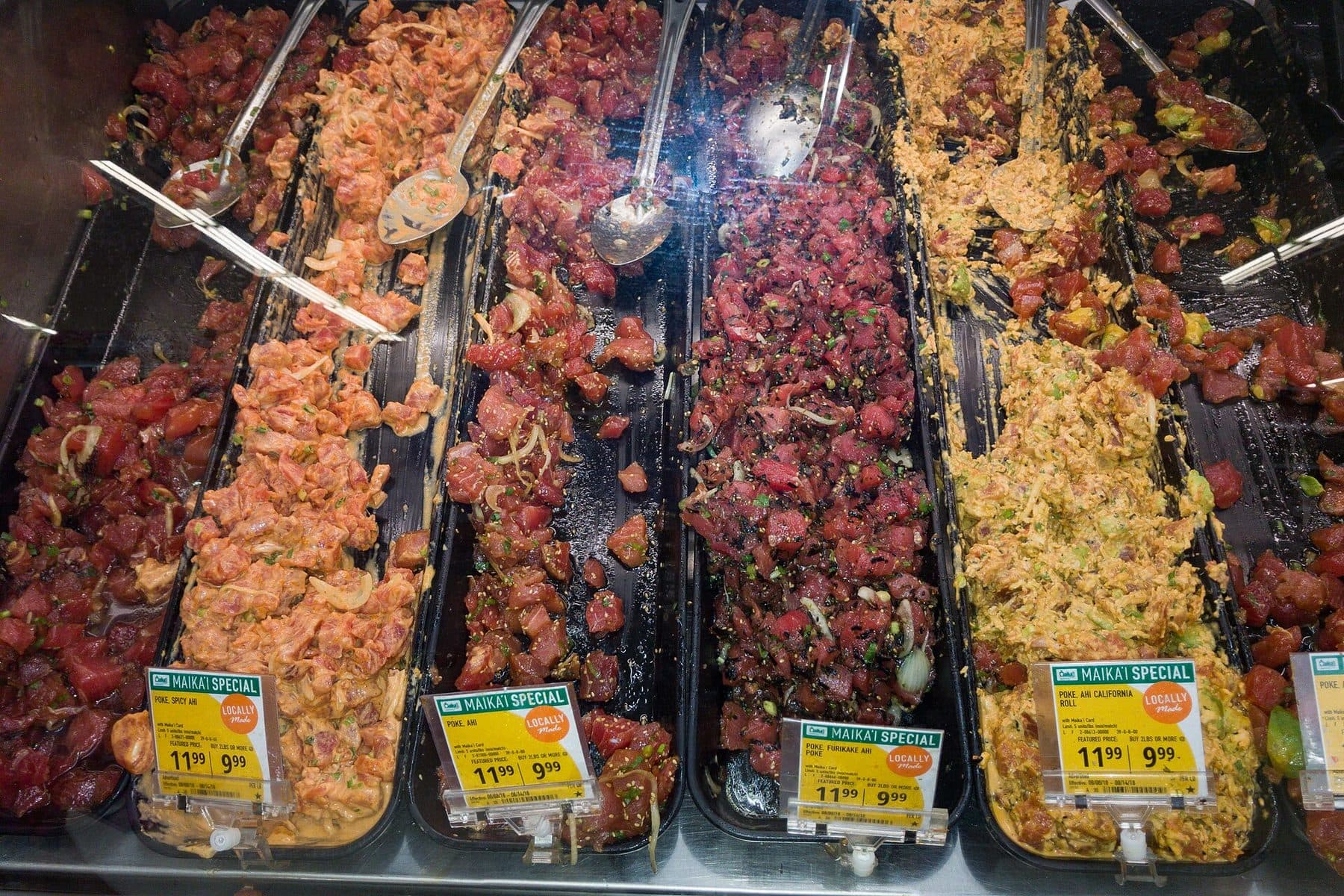 Trays of ahi and other poke behind the glass at a Hawaiʻi poke counter