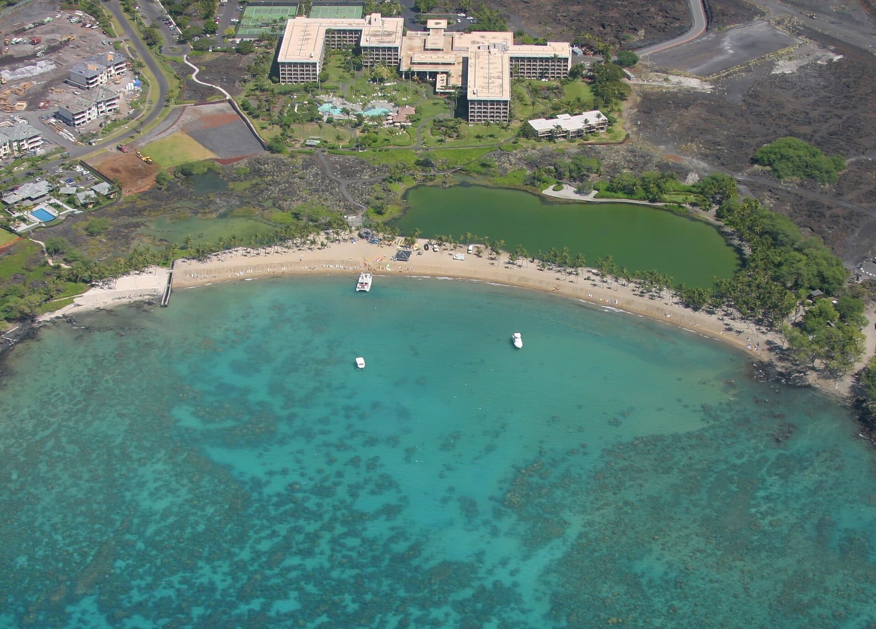 Aerial view of ʻAnaehoʻomalu Bay’s reef-sheltered water, its beach, and the fishpond behind it in Waikōloa (the Kohala Coast area, not the hotel)
