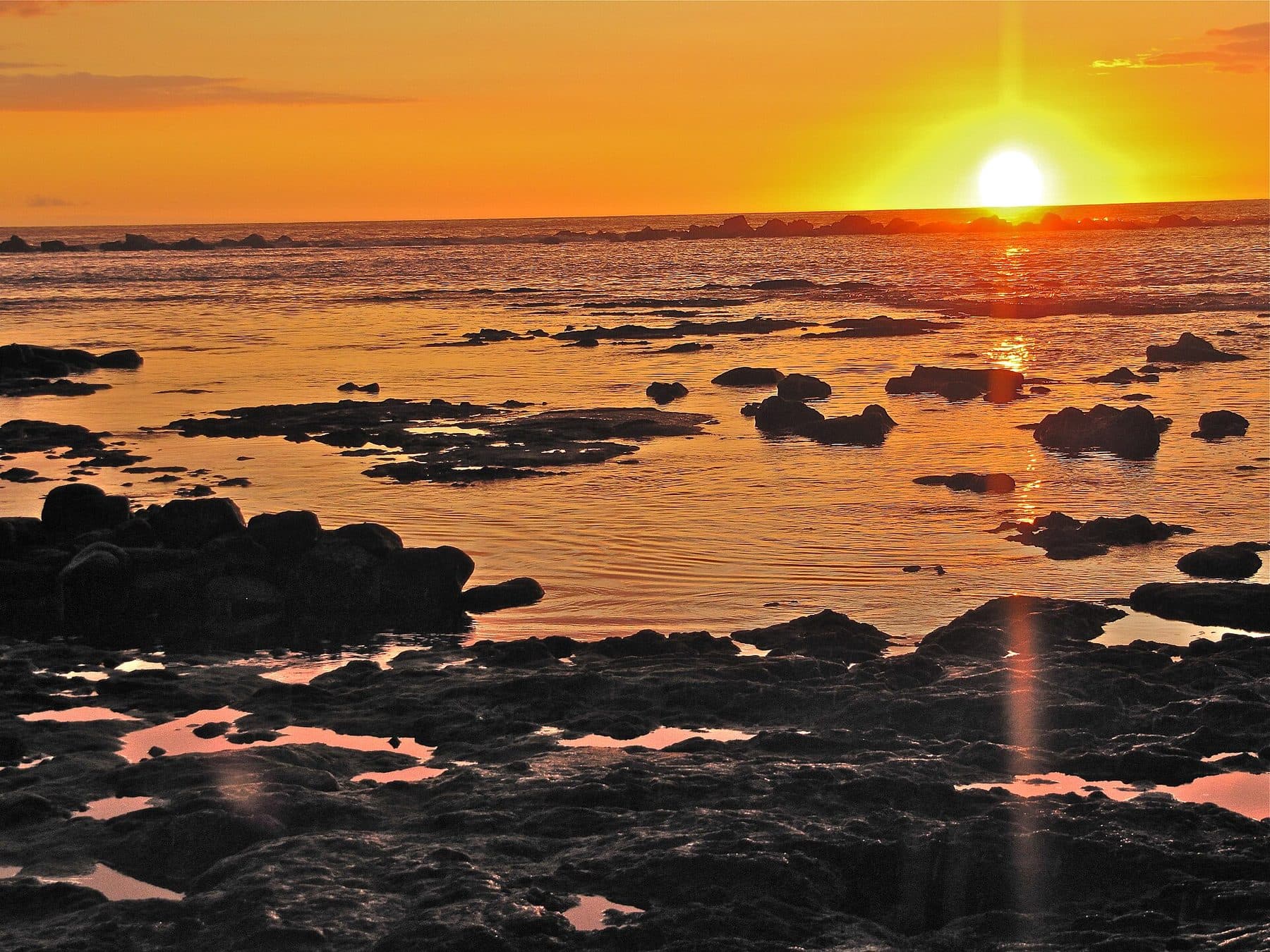 Sunset glowing over the lava-rock shoreline and tide pools at Kahaluʻu Beach Park