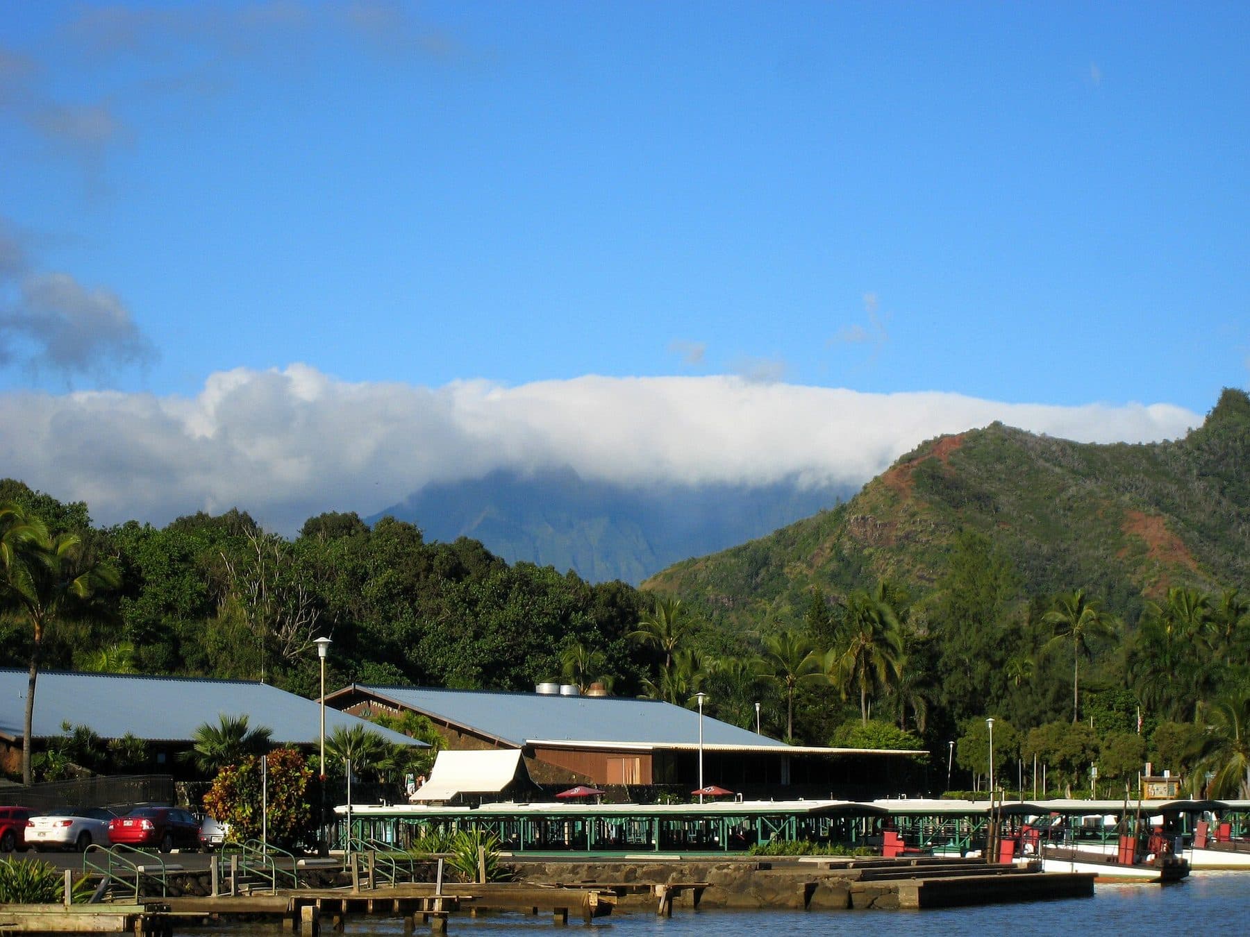 Buildings and boats along the Wailua River below green mountains