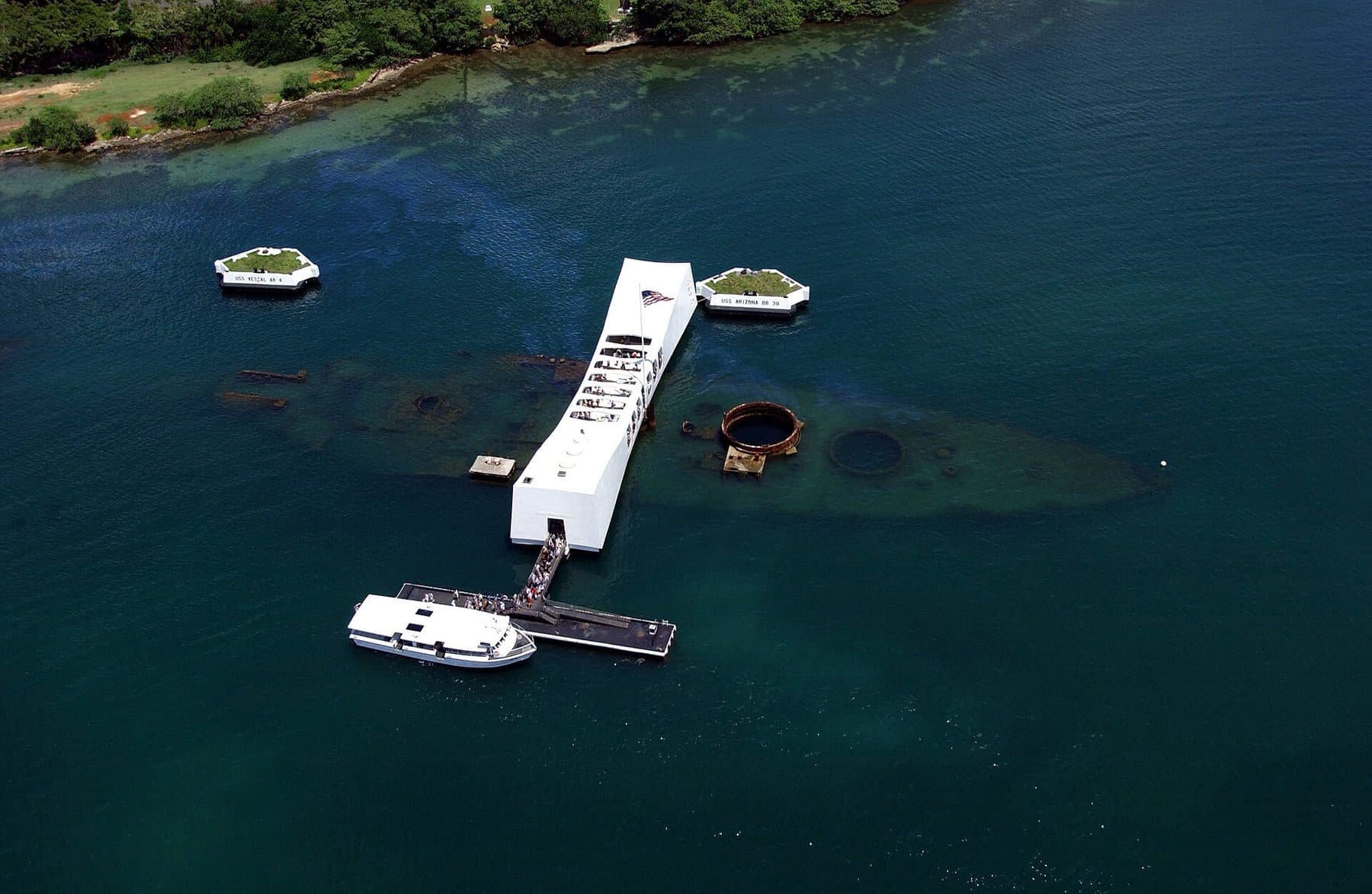 Aerial view of the USS Arizona Memorial in Pearl Harbor with a visitor shuttle boat docked